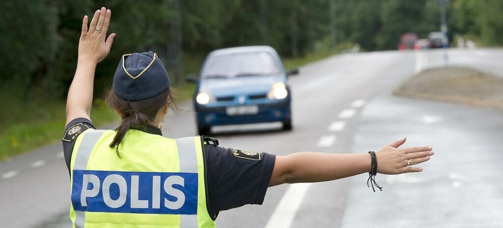 En polisbevakare vinkar med armarna i luften. (AI text)