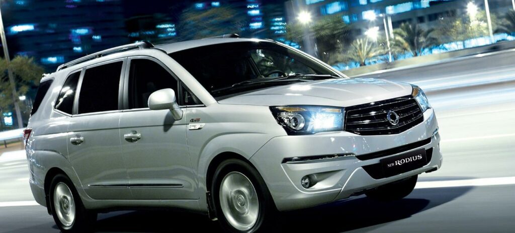 En silverbil kör nedför en stadsgata på natten. (AI text)