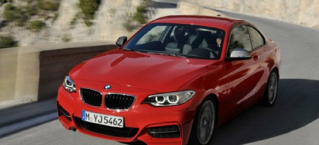 BMW M2 coupén kör nerför en bergsväg. (AI text)