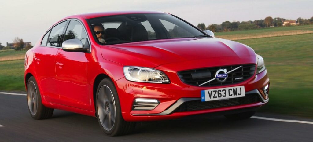 En röd Volvo V40 kör nedför en landsväg. (AI text)