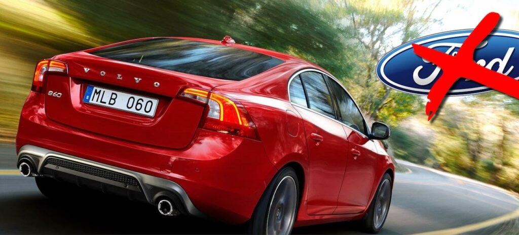 En röd Volvo S60 kör nedför en väg med ordet "Ford" på den. (AI text)