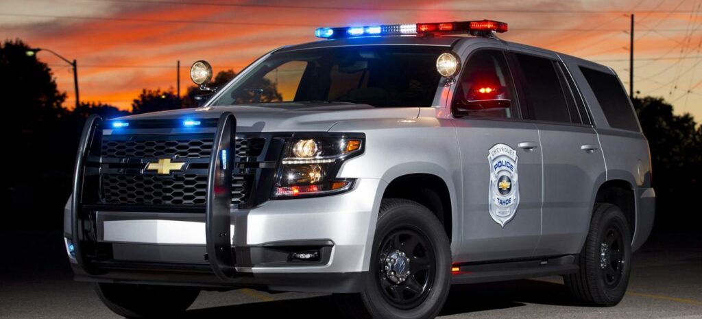 En polisbil med pågående blinkers på kvällen. (AI text)