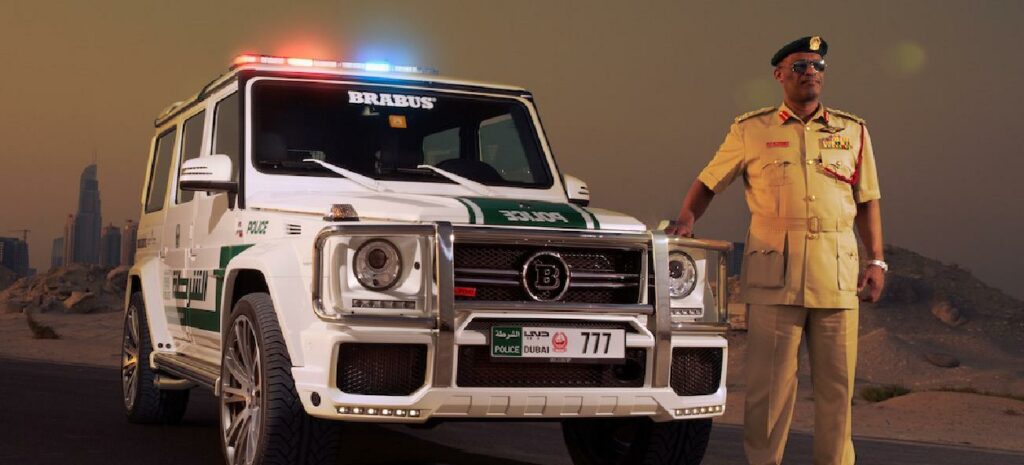 En polis står bredvid en patrullbil i öknen. (AI text)