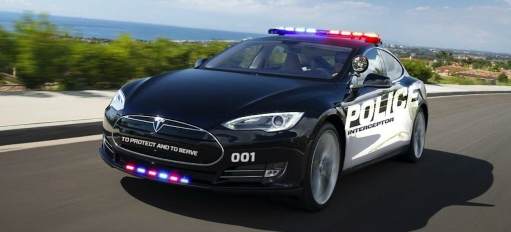 En Tesla Model S, utrustad som polisbil, kör nerför vägen. (AI text)