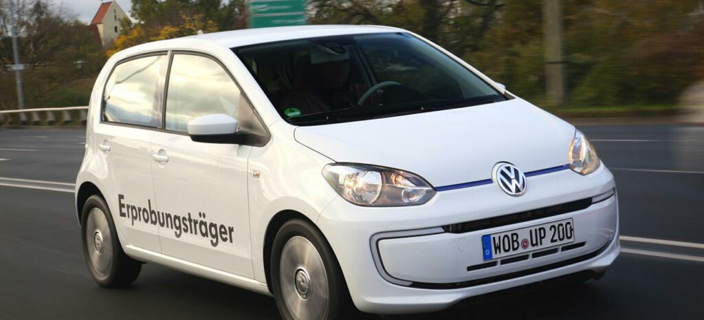En Volkswagen up! kör nerför vägen. (AI text)