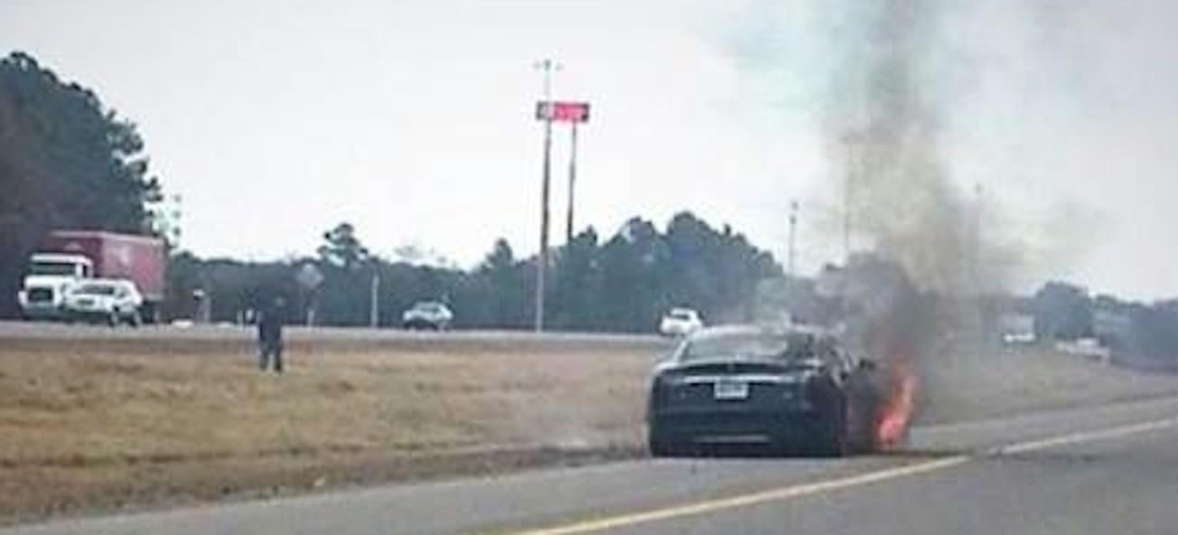 En bil står i brand vid vägkanten. (AI text)