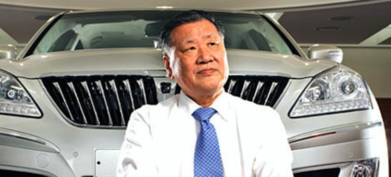 En man i kostym sitter bredvid en bil. (AI text)