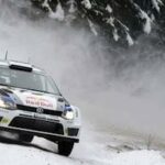 En Volkswagen WRC-bil kör genom snön. (AI text)