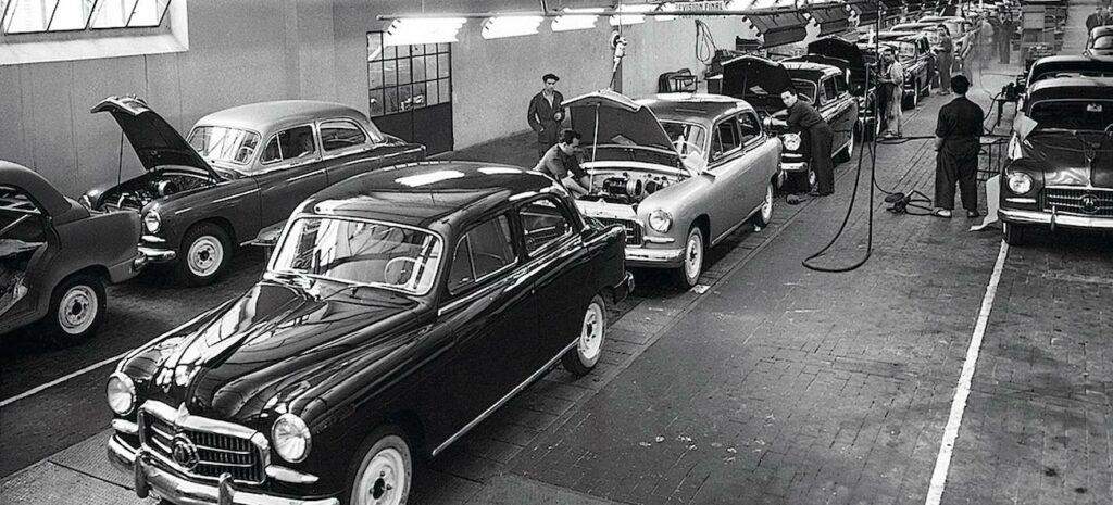 En fabrik med bilar i bakgrunden. (AI text)