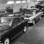 En fabrik med bilar i bakgrunden. (AI text)