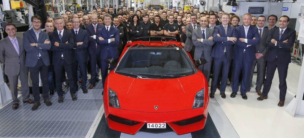 En grupp personer står framför en röd sportbil. (AI text)