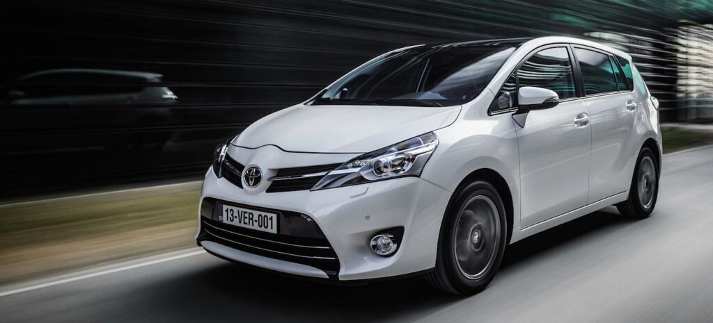 En vit Toyota Aygo kör nerför en väg. (AI text)