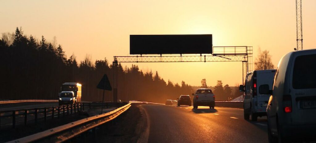 En bil kör på en motorväg vid solnedgång. (AI text)