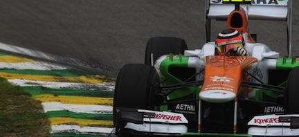 En grön och orange formel 1-bil kör nerför en bana. (AI text)