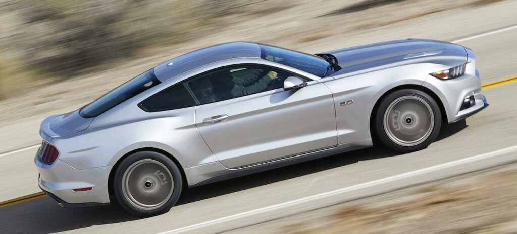 en silverfärgad ford mustang kör nedför en landsväg (AI text)