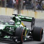 En grön Formula 1-bil kör nerför banan. (AI text)