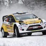 En rallybil kör genom snön. (AI text)