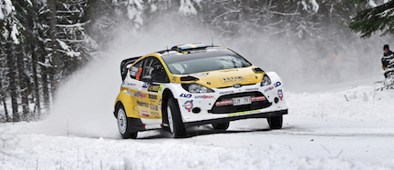En rallybil kör genom snön. (AI text)