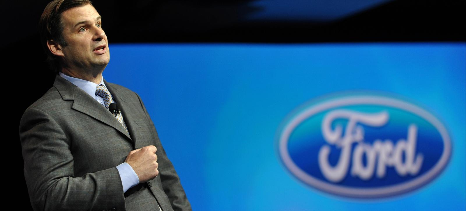 En man i kostym står framför ett Ford-logotyp. (AI text)