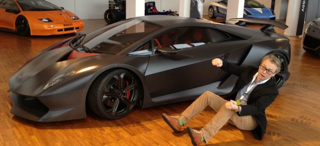 En man sitter på golvet bredvid en Lamborghini. (AI text)