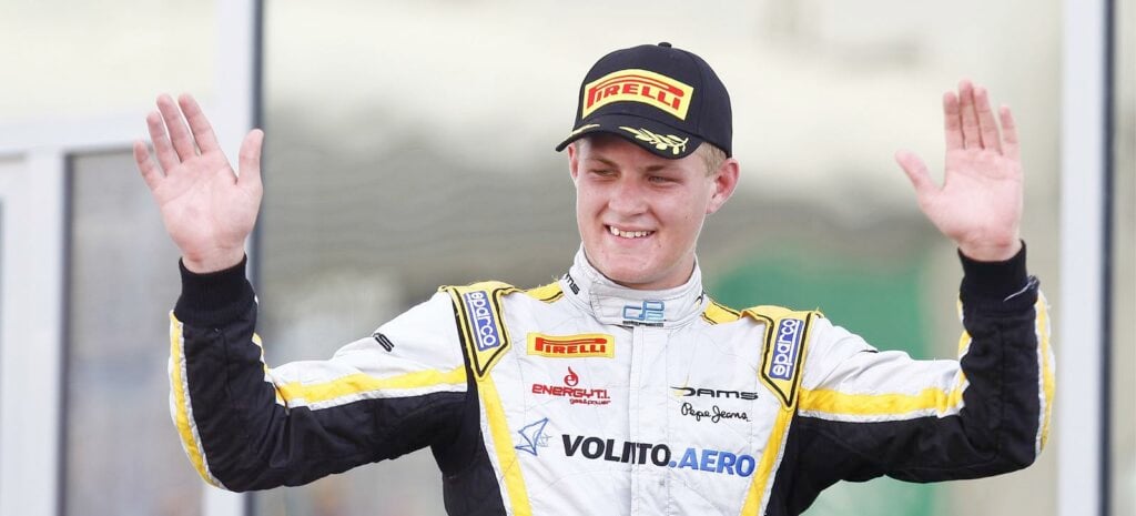 En racerförare vinkar till publiken efter att ha vunnit loppet. (AI text)