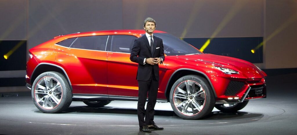 En man står bredvid en röd SUV. (AI text)