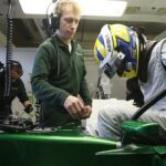 En racingbil i en garage där en mekaniker arbetar på den. (AI text)