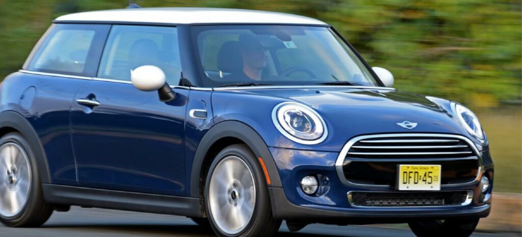 En blå Mini Cooper kör längs en landsväg. (AI text)