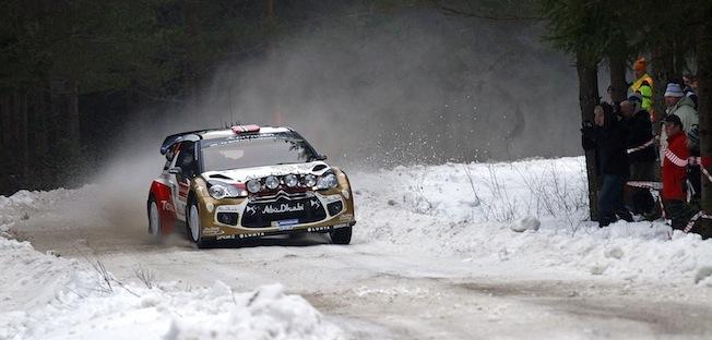 En rallybil körer nedför en snöig väg. (AI text)