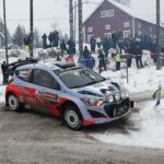 En rallybil körer längs en snöig väg. (AI text)