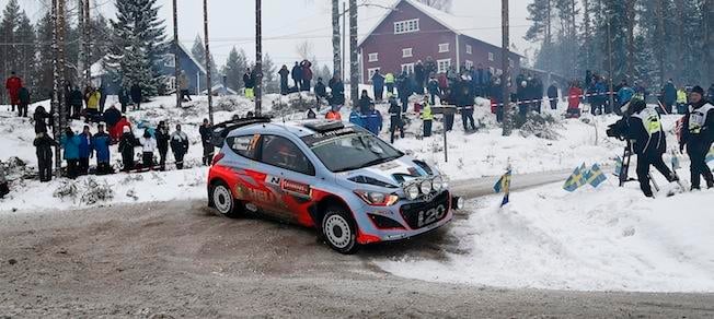 En rallybil körer längs en snöig väg. (AI text)