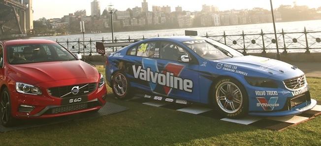 En racerbil och en parkerad racerbil framför en bro. (AI text)