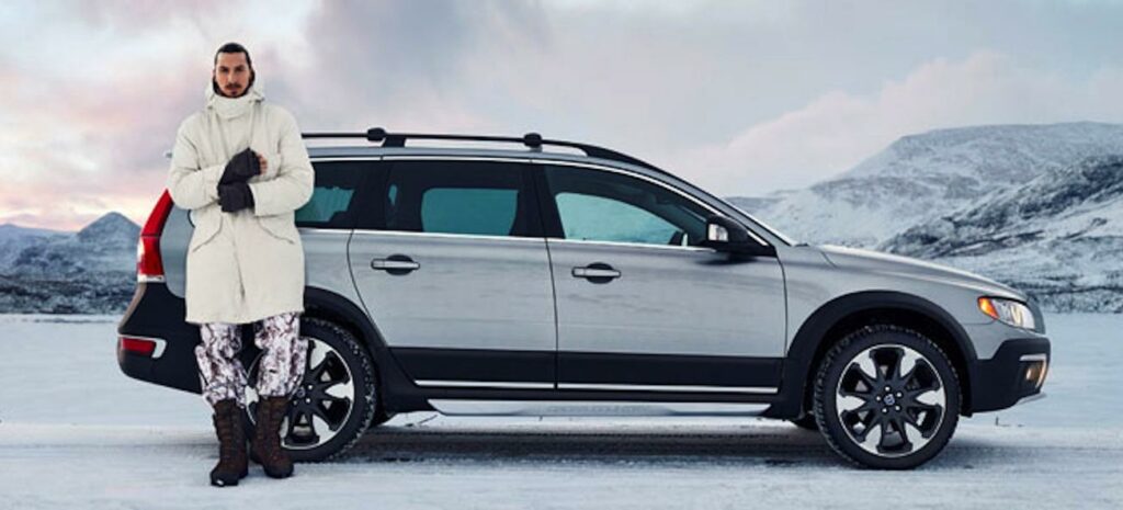 En man står bredvid en bil i snön. (AI text)