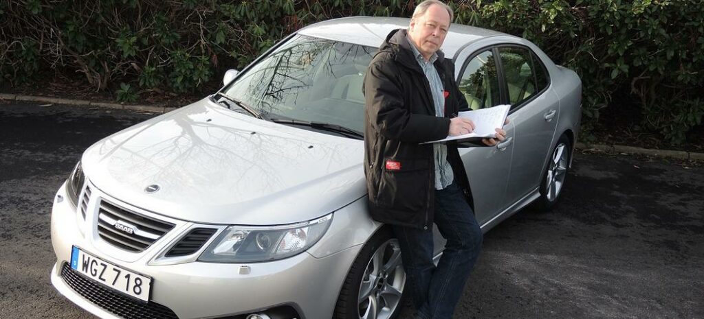 En man står bredvid en bil. (AI text)