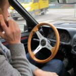 En man kör bil samtidigt som han pratar i sin mobiltelefon. (AI text)