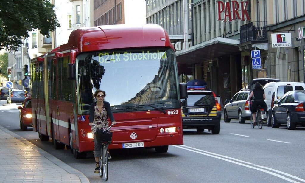 En stadsgata med en buss och en bil. (AI text)