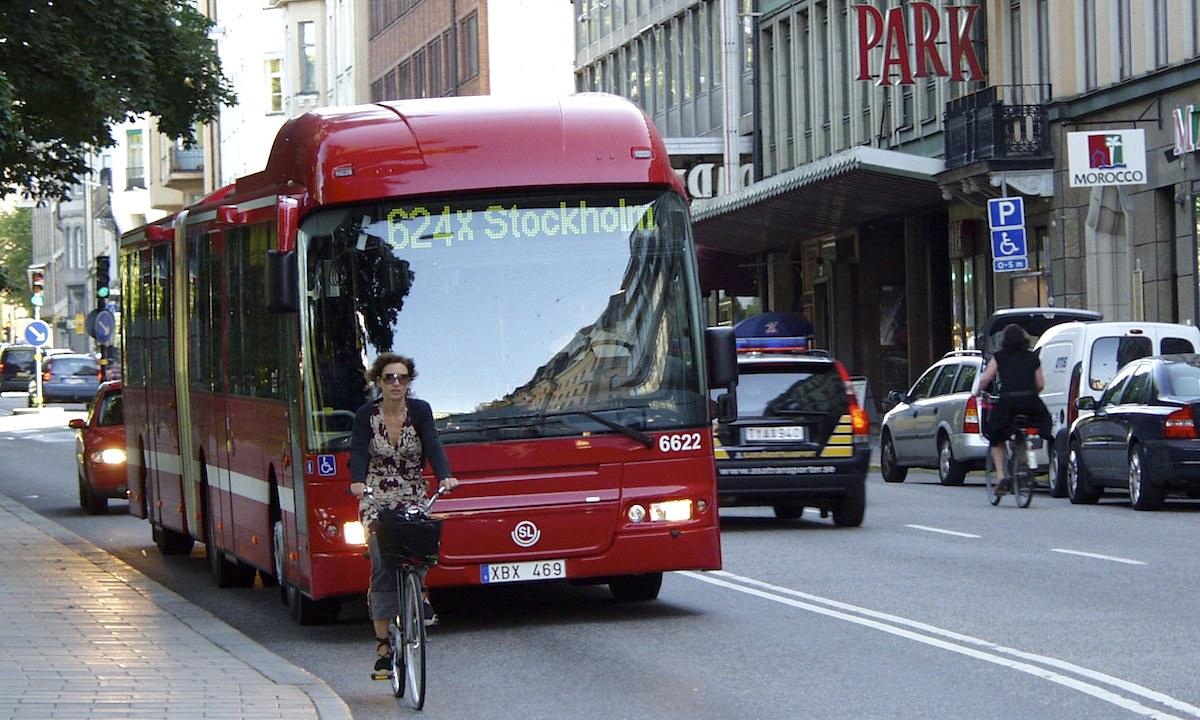 En stadsgata med en buss och en bil. (AI text)