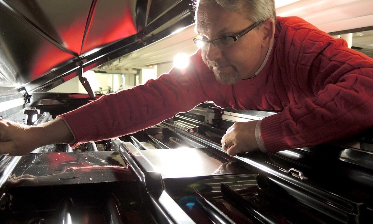 En man lastar en piano i en bil. (AI text)