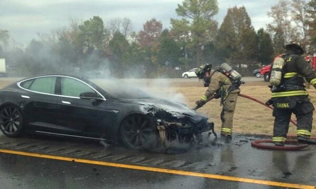 En brandman släcker eld på en Tesla Model S. (AI text)