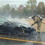 En brandman släcker eld på en Tesla Model S. (AI text)