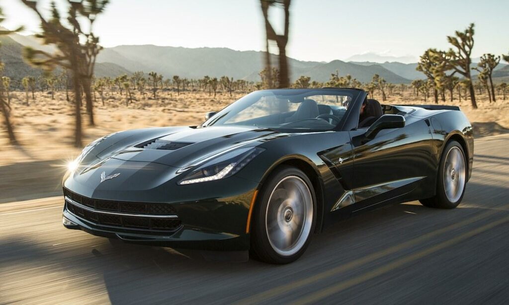 En grön Chevrolet Corvette Stingray kör nedför en ökenväg. (AI text)