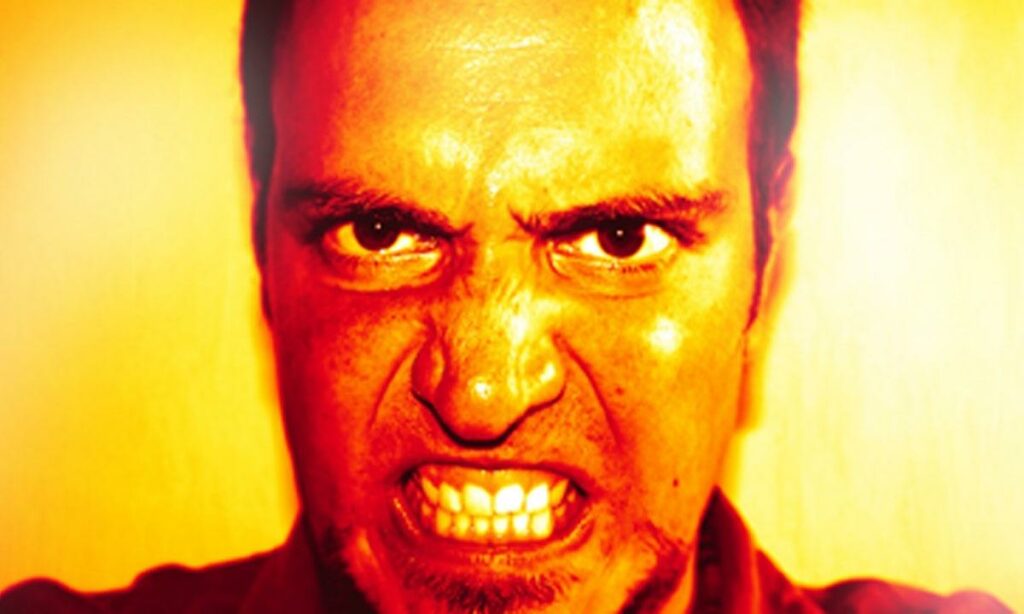 En man i en röd skjorta och en röd hatt ser arg ut. (AI text)