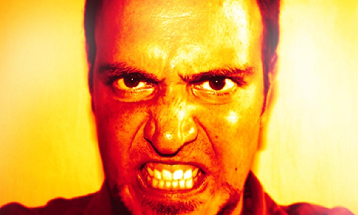 En man i en röd skjorta och en röd hatt ser arg ut. (AI text)