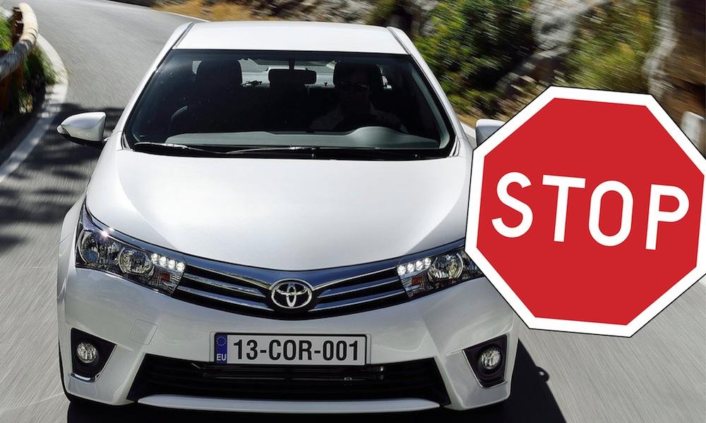 En vit Toyota Corolla kör nerför en krökig väg med en hastighetsgräns. (AI text)