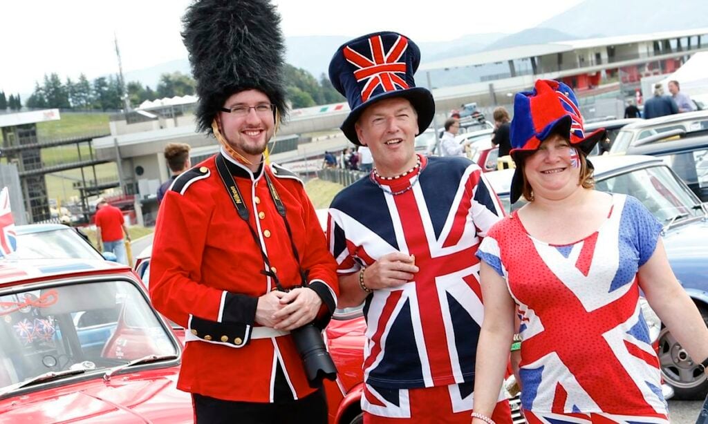 En grupp personer klädda i brittiska flaggor och en bil. (AI text)