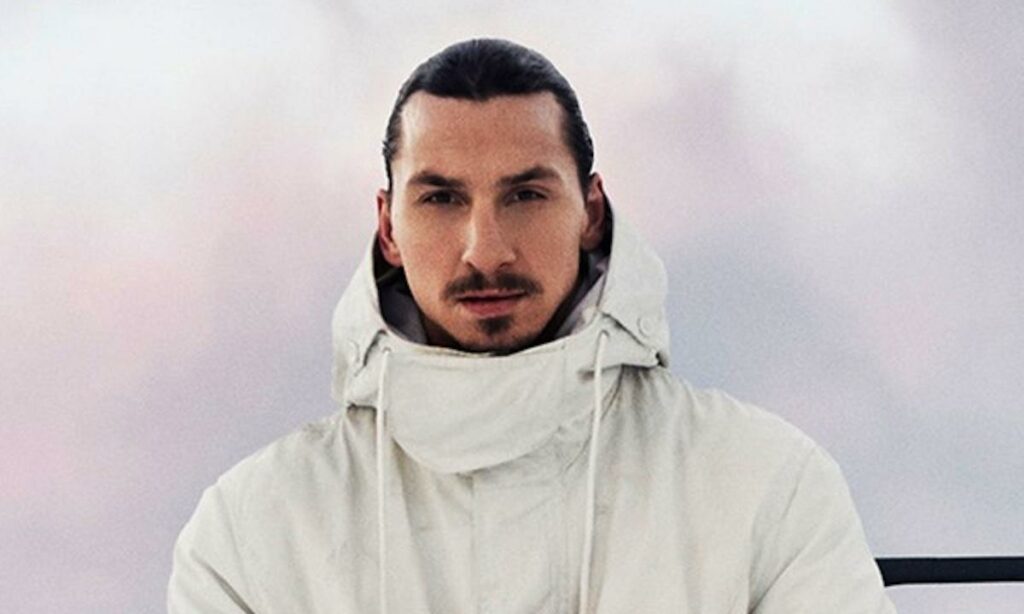 En man i ett vit rock står framför en vit bil. (AI text)