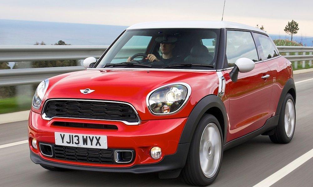 En röd Mini Countryman kör ner en väg. (AI text)