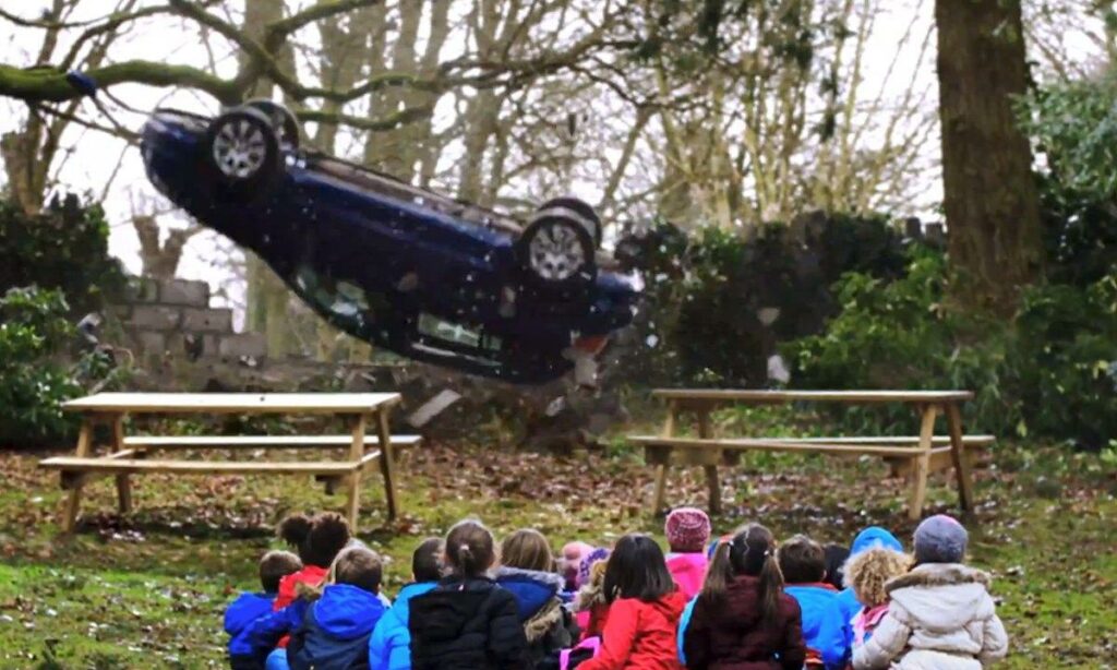 Barngruppen tittar på när en bil vält i skogen. (AI text)