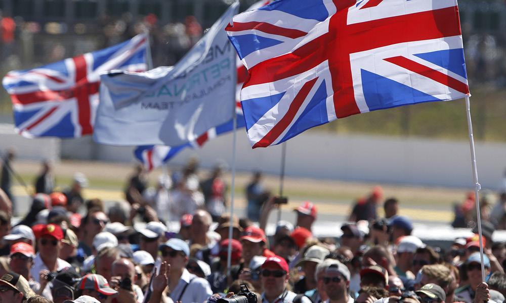 En skara människor som vajar med brittiska flaggor på racbanan. (AI text)
