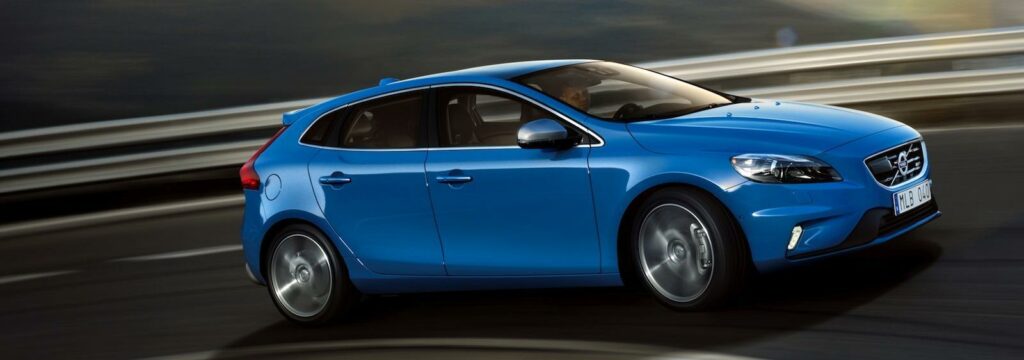 En blå Volvo V40 kör på en väg. (AI text)